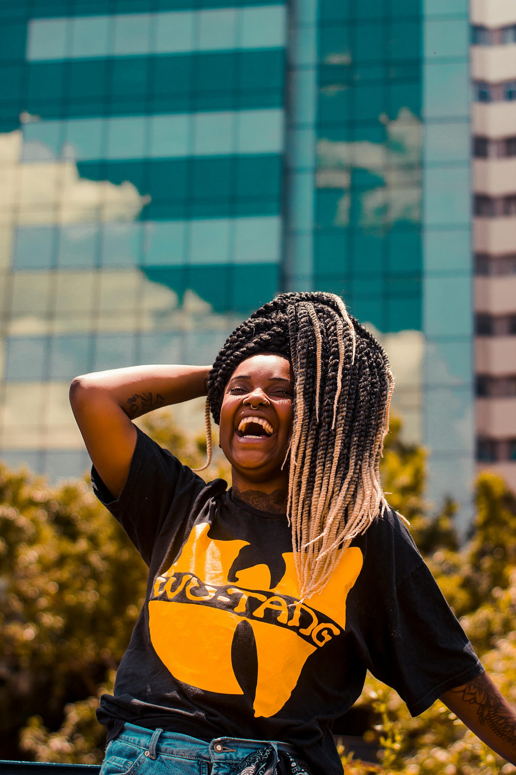 Vibrant portrait of a joyful young black woman with dreadlocks, enjoying a sunny day outdoors.